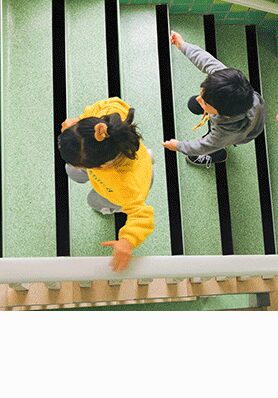 Children on a green playground ramp fitted with black anti-slip tape strips
