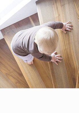Toddler climbing indoor wooden stairs fitted with clear anti-slip tape