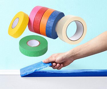Colored masking tape rolls with a hand applying blue tape